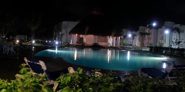 Hermosa vista de la alberca y Palapa por la noche.