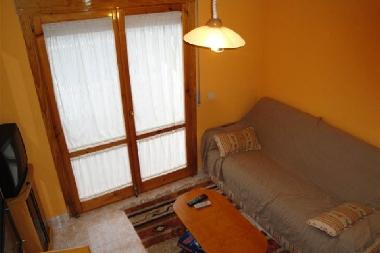 salon con sofa cama simple, TV, y salida al jardn