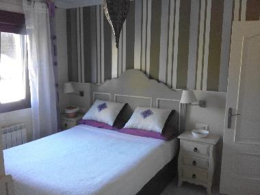 Habitacin principal con cama de 1.50, armario empotrado y ventana con vistas al jardn.